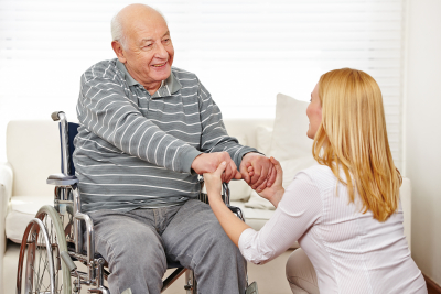 woman holding hands of senior man in wheelchair